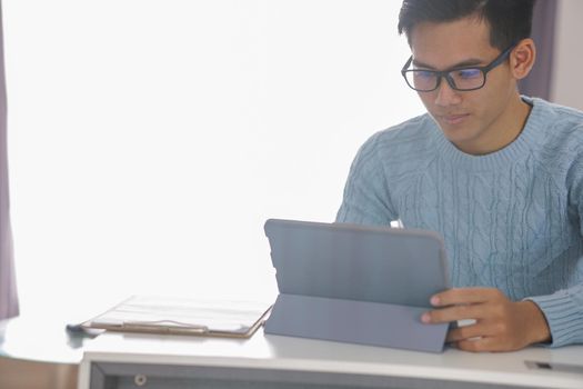 asian young teenage student man teenager entrepreneur working with tablet studying learning online at home. e-learning webinar meeting. social distance in covid pandemic
