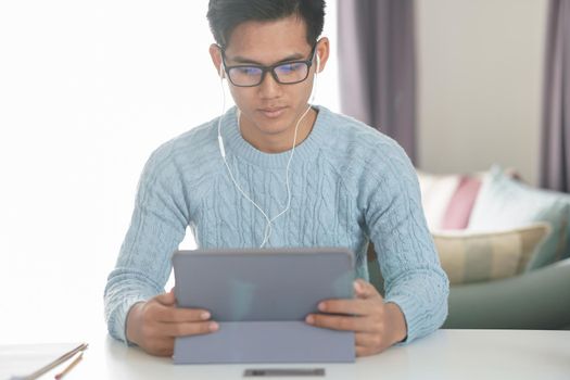 asian young teenage student man entrepreneur wear earphones working by video call conference studying learning online at home. e-learning webinar meeting. social distance in covid pandemic