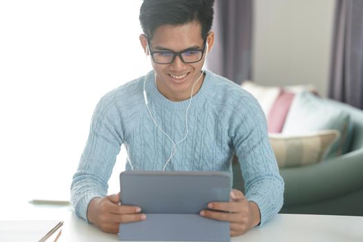 asian young teenage student man entrepreneur wear earphones working by video call conference studying learning online at home. e-learning webinar meeting. social distance in covid pandemic