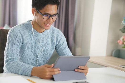 asian young teenage student man entrepreneur wear earphones working by video call conference studying learning online at home. e-learning webinar meeting. social distance in covid pandemic