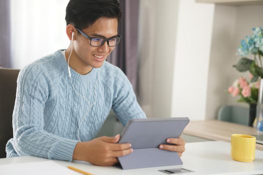 asian young teenage student man entrepreneur wear earphones working by video call conference studying learning online at home. e-learning webinar meeting. social distance in covid pandemic