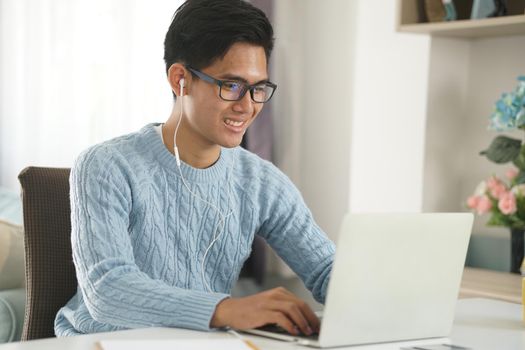 asian young teenage student man entrepreneur wear earphones working by video call conference studying learning online at home. e-learning webinar meeting. social distance in covid pandemic