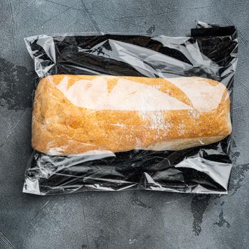Loaf of fresh baked artisan whole grain ciabatta bread in a market bag, on gray background, top view flat lay