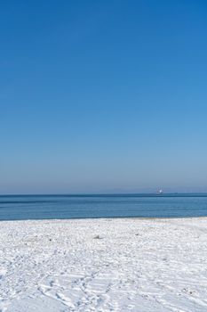 Seascape with a beach in snow and bright sun