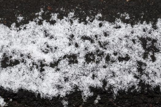 Dirty tracks of snow on asphalt on a small german road.