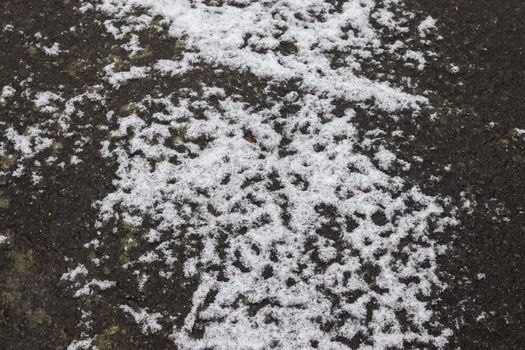 Dirty tracks of snow on asphalt on a small german road.