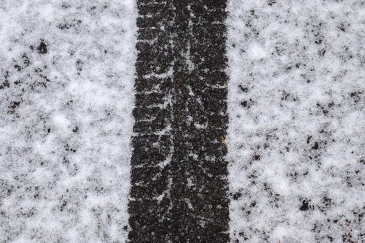 Dirty tracks of snow on asphalt on a small german road.