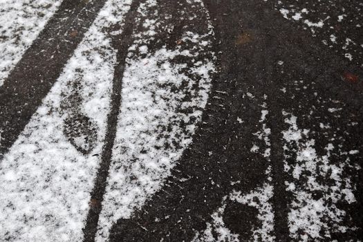 Dirty tracks of snow on asphalt on a small german road.