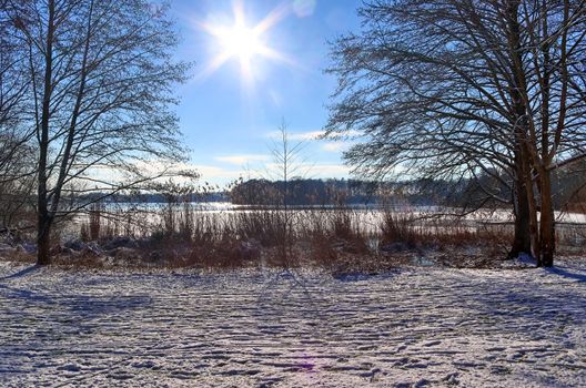 Snow covered frozen lake landscape in northern europe on a sunny day