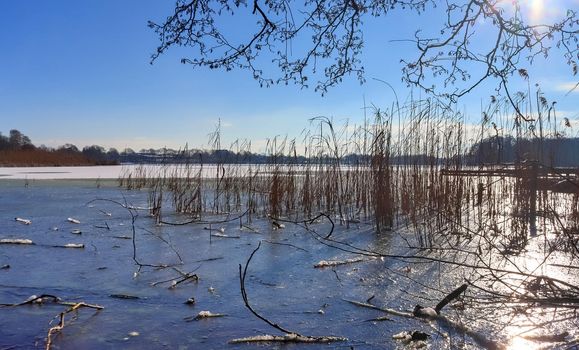 Snow covered frozen lake landscape in northern europe on a sunny day