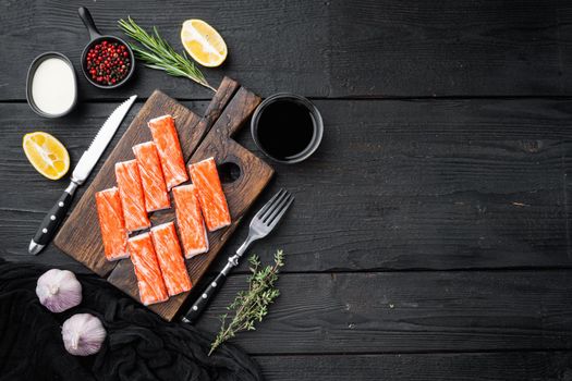 Fresh Crab meat stick surimi set, on wooden cutting board, on black wooden table background, top view flat lay , with copyspace and space for text
