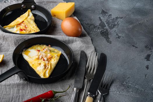 Fried breakfast omelette with a crab meat and cheese, on frying iron pan, on gray background , with copyspace and space for text