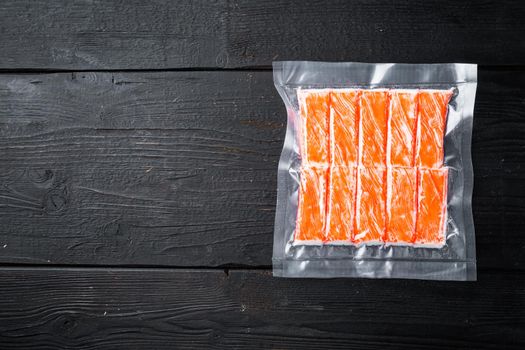 Crab stick surimi vacuum pack set, on black wooden table background, top view flat lay , with copyspace and space for text