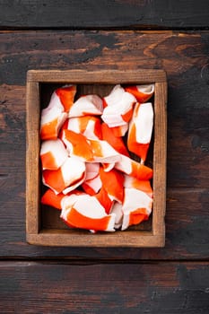 Fresh Crab meat stick surimi set, in wooden box, on dark wooden background, top view flat lay