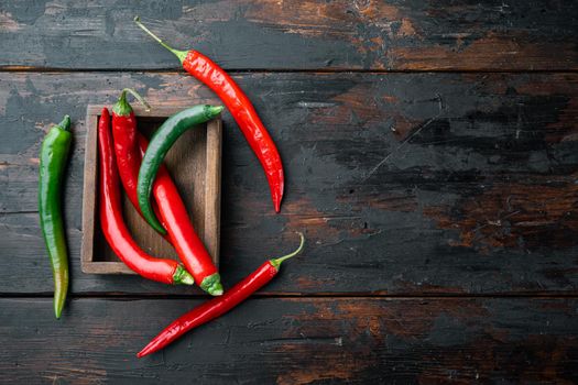 Red and green chili pepper set, in wooden box, on dark wooden background, top view flat lay , with copyspace and space for text