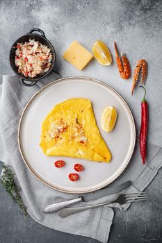 Fried breakfast omelette with a crab meat and cheese, on plate, on gray background, top view flat lay