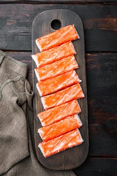 Asian snack surimi set, on wooden cutting board, on dark wooden background, top view flat lay