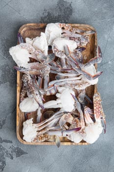 Frozen raw blue swimming crab parts set, on wooden tray, on gray background, top view flat lay