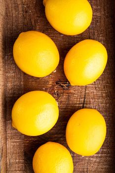 Ripe lemons set, in wooden box, on gray background, top view flat lay