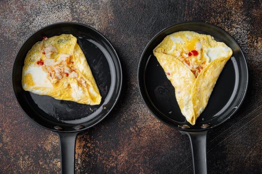 Spanish omelette, fresh red chilli, brown and white crabmeat, lemon, Cheddar cheese, eggs fried, on frying iron pan, on old dark rustic background, top view flat lay
