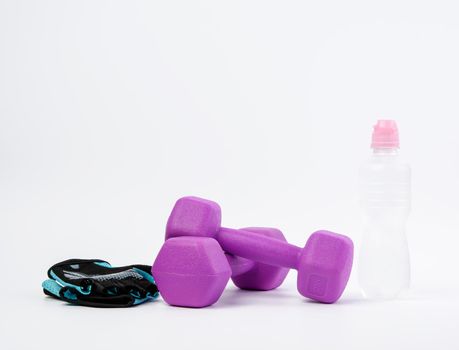 blue sports gloves, pair of purple dumbbells and and bottle of water on a white background, healthy lifestyle