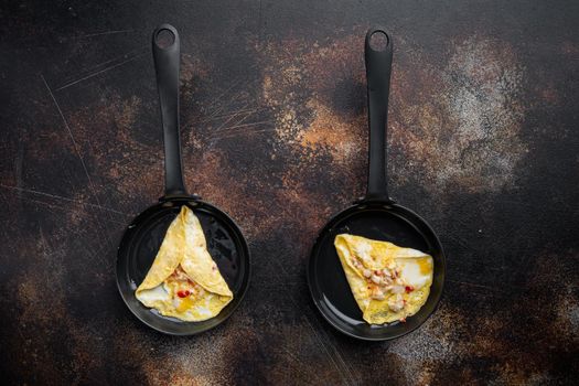 Thai Asian omelette, fresh red chilli, brown and white crabmeat, lemon, Cheddar cheese and eggs, on frying iron pan, on old dark rustic background, top view flat lay