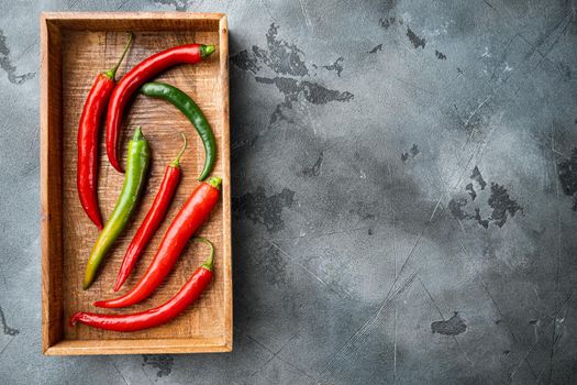 Red and green chili pepper set, in wooden box, on gray background, top view flat lay , with copyspace and space for text