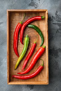 Ripe Red and green chili pepper set, in wooden box, on gray background, top view flat lay