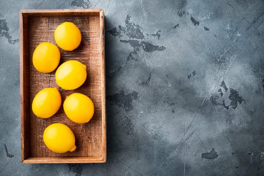 Fresh lemons set, in wooden box, on gray background, top view flat lay , with copyspace and space for text