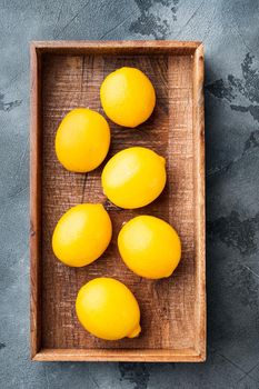 Ripe lemons set, in wooden box, on gray background, top view flat lay