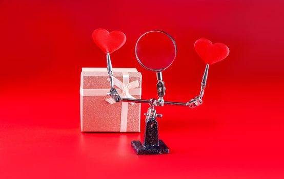 Abstract Valentines Day background with engineering tool third hand holding hearts and gift on red background and copyspace