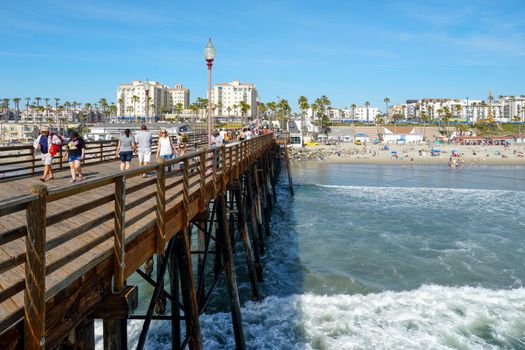 Tourist walking on the Oceanside Pier during blue summer day, Oceanside, northern San Diego, California. Wooden pier on the western United States coastline. Famous for fisher. Febraury 22n, 2020