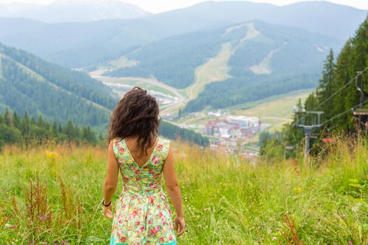 Happy gorgeous girl enjoy mountain view stay in summer dress on the hill with breathtaking  mountain landscape.