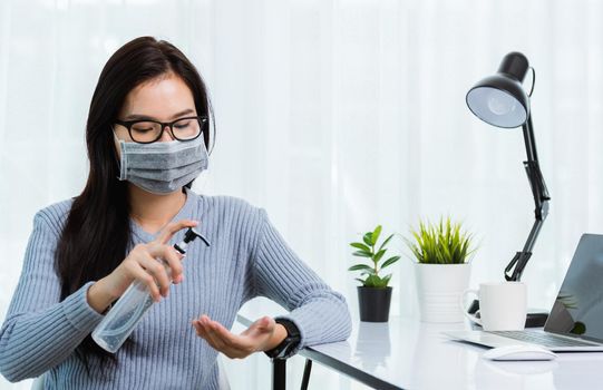 Asian young business beautiful woman wearing face mask protective working from home office with laptop computer desk he quarantines disease coronavirus and cleaning hands by sanitizer alcohol gel pump