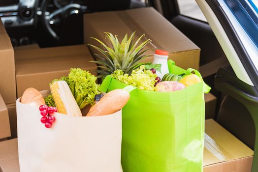 Grocery service giving fresh vegetables and fruits and food in green cloth bag and wooden basket on the back car ready delivery to send woman customer