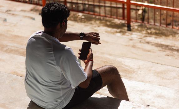 Close up Asian young athlete sport runner black man wear modern time smart watch and sync to a smartphone check running result after a training run at the outdoor, healthy exercise workout technology