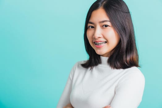 Young beautiful Asian woman smiling with crossed arms, Portrait of positive confident female stand cross one's arm, studio shot isolated on a blue background