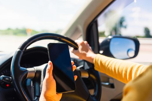 Asian woman inside a car and using a hand holding mobile smartphone blank screen while driving the car in the morning during going to work on highway, Transportation and vehicle concept
