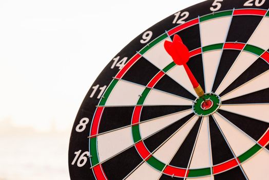 Dart arrow hitting to center on bullseye (bull's-eye) dartboard is the target of purpose challenge business at sunset, expert marketing strategy target, objective financial and goal success
