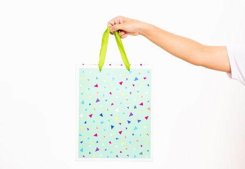 Closeup women hand holding a colorful green shopping bag, studio shot isolated on white background, female holds in hand white clear empty blank craft paper gift bag for purchases