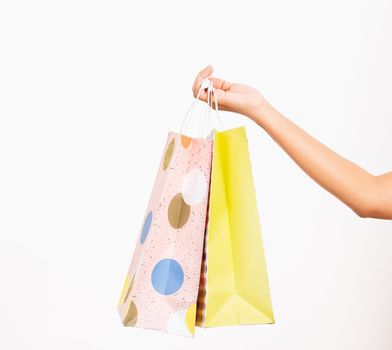 Closeup women hand holding colorful multicolor shopping bag many packets isolated on white background, female holds in hand white clear empty blank craft paper gift bag, shopping day concept