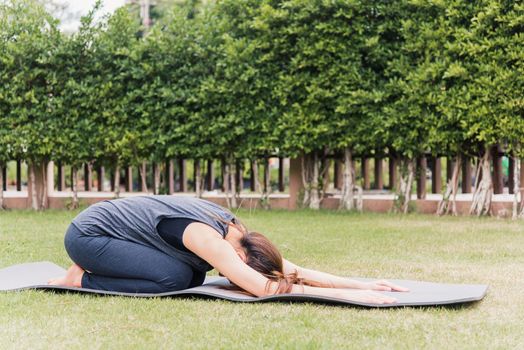 Asian young woman practicing yoga outdoors in meditate pose sitting on green grass with closed eyes in nature a field garden park, Stretching, meditation, exercise health care concept