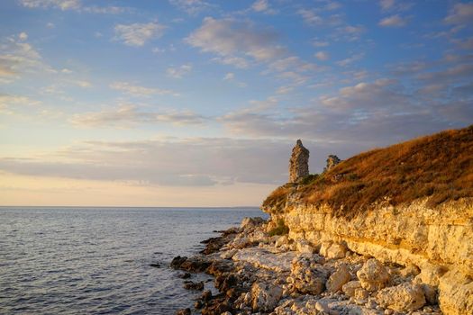 Rocky coastline illuminated by the light of the setting sun against the sea. Seascape with beautiful rock formations near the shore of the Chersonese.