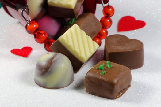 Saint Valentine's day chocolate truffle bucket with red hearts on textured white surface