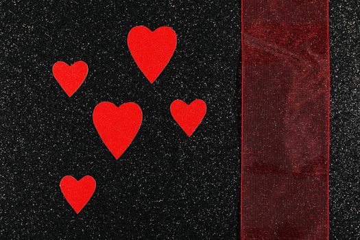 Saint Valentine's day red hearts and broad red ribbon design on textured black background