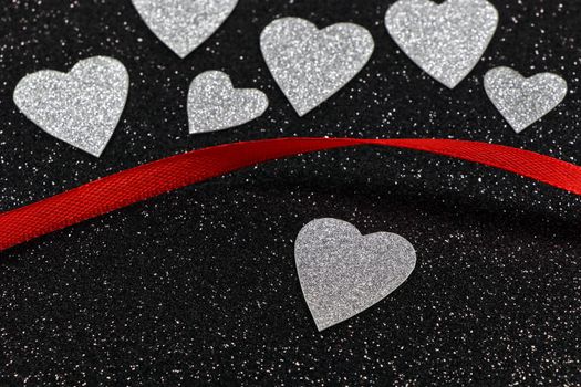 Saint Valentine's day silver hearts and red ribbon design on textured black background