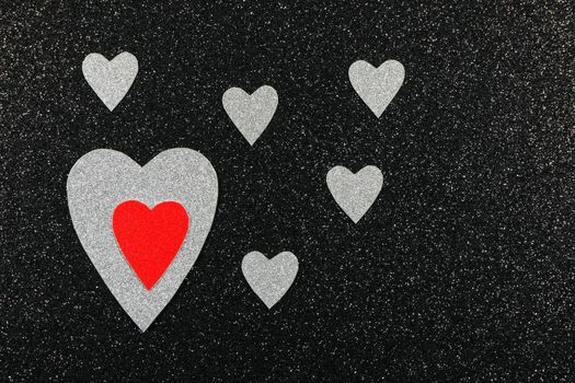 Saint Valentine's day red and silver hearts design on textured black background