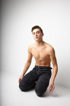 A man with a naked torso is kneeling studio posing attractive look. High quality photo