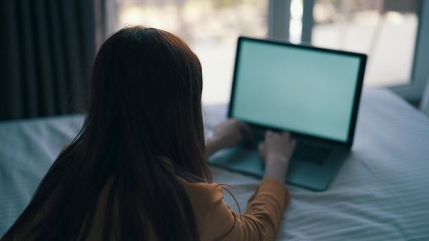 woman lying on bed working in front of laptop at home internet. High quality photo