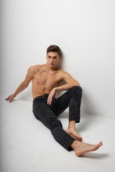 Man sits on the floor in black trousers nude torso posing luxury model. High quality photo